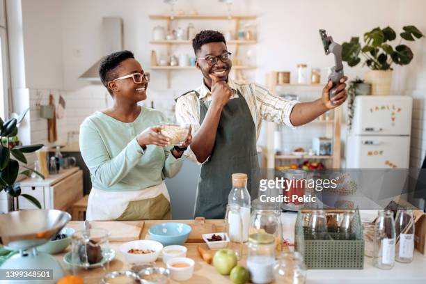 junges paar, das in ihrer heimischen küche essen vlog macht - fruit smoothie instagram stock-fotos und bilder