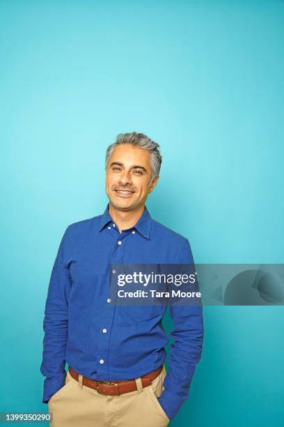 portrait of handsome mature man against blue background - grey shirt stock pictures, royalty-free photos & images