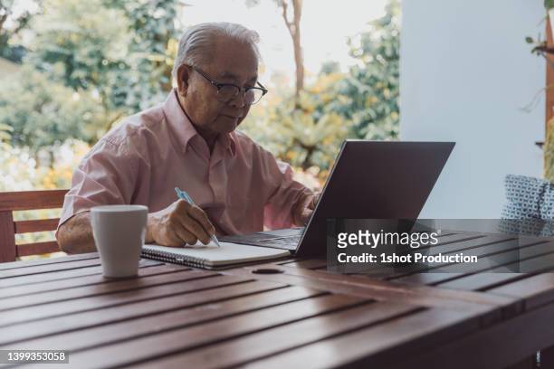 senior man working at home using laptop in balcony. - vpn stock pictures, royalty-free photos & images