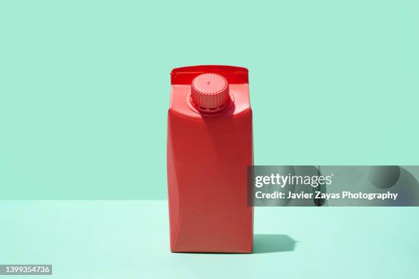 red small milk or juice box on green background - milk carton - fotografias e filmes do acervo