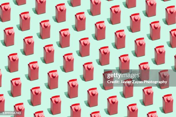 many red small milk or juice boxes on green background - galón fotografías e imágenes de stock