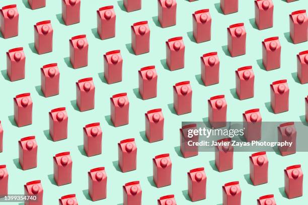 many red small milk or juice boxes on green background - juice box stock pictures, royalty-free photos & images