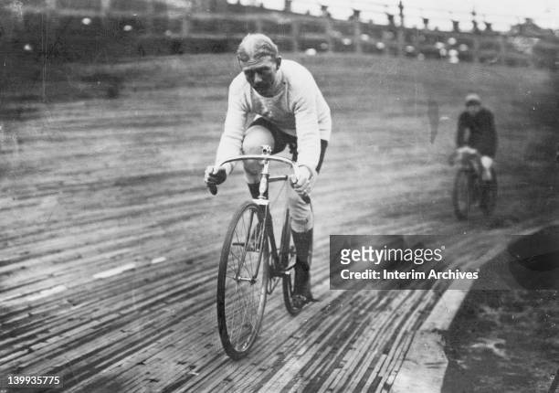 View of American professional cyclist Robert Walthour pictured on his bicycle, riding on a wooden tracked velodrome during a six day race, December...