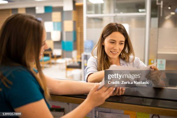 young woman is filling documents on the clinic reception - human body part stock pictures, royalty-free photos & images