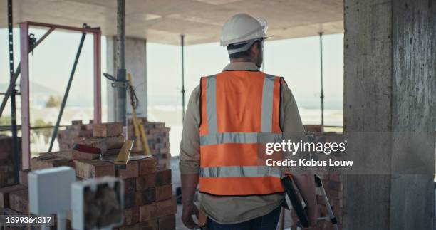 a building contractor inspecting a construction site. rear view of a man walking through a building during an architecture project - waistcoat stock pictures, royalty-free photos & images