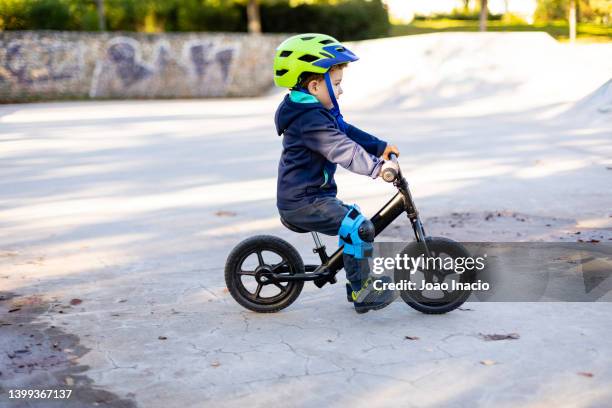toddler boy riding balance bike in a skatepark - un seul petit garçon photos et images de collection