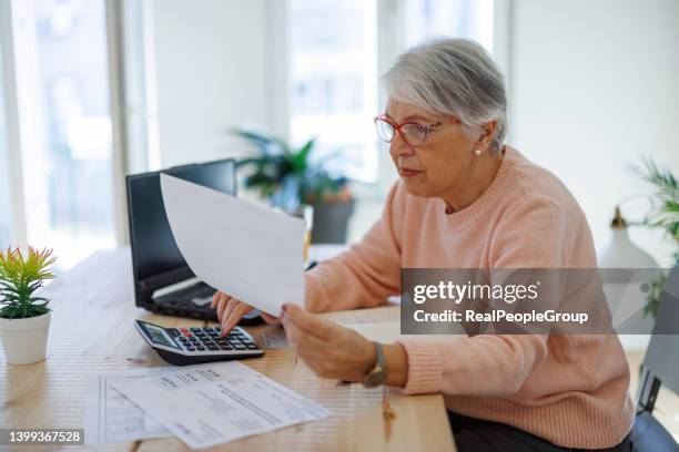 nachdenkliche ältere frau, die den laptop benutzt, um rechnungen online zu hause zu bezahlen. ältere geschäftsfrau arbeitet am computer. - real people serious not looking at camera not skiny stock-fotos und bilder