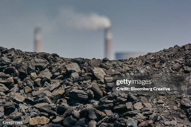 a pile of coal by smokestacks - coal power plant stockfoto's en -beelden