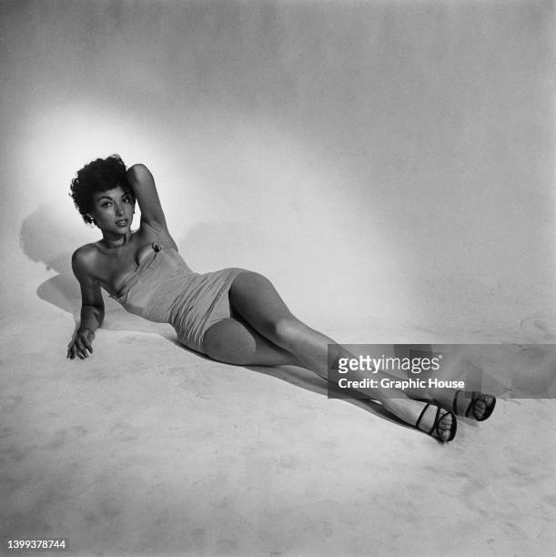 Puerto Rican singer, dancer and actress Rita Moreno, wearing a strapless bathing costume, supports herself using her right arm, her left arm behind...