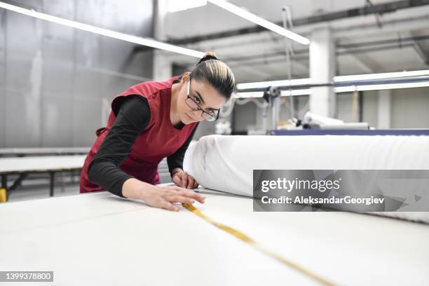 ouvrière du textile spécialisée dans la mesure et la préparation de rouleaux de matériaux en usine - fabric rolls photos et images de collection