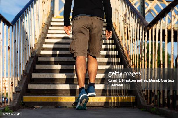 rearview of a man climbing up the stairs of a footbridge - short photos et images de collection