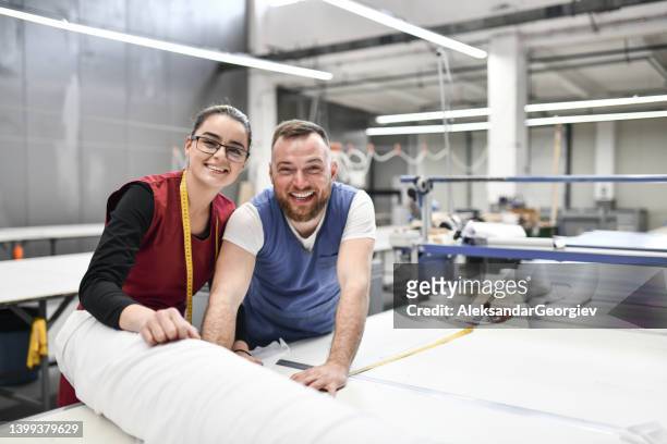 portrait de collègues hommes et femmes d’usines textiles mesurant et étalant des rouleaux de matériaux - fabric rolls photos et images de collection