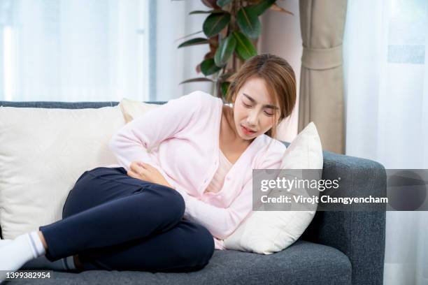 woman on sofa bed with stomach pain - colite foto e immagini stock
