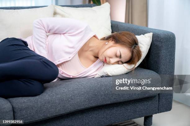 woman on sofa bed with stomach pain - colite foto e immagini stock