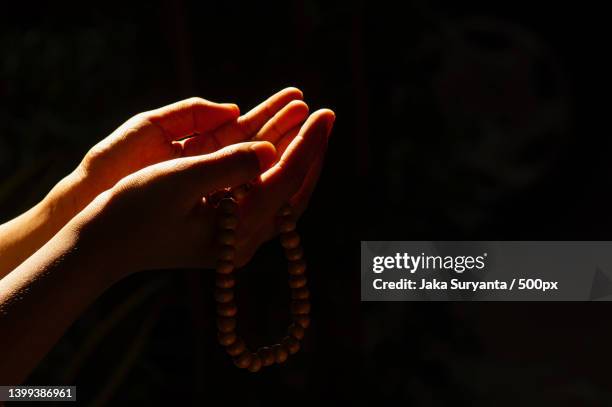 hands of a child praying with a prayer beads on a dark background and backlight,indonesia - trust god stock pictures, royalty-free photos & images