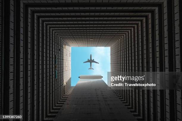airplane flying over courtyard of skyscraper in hong kong city photographed from below - aircraft stock pictures, royalty-free photos & images