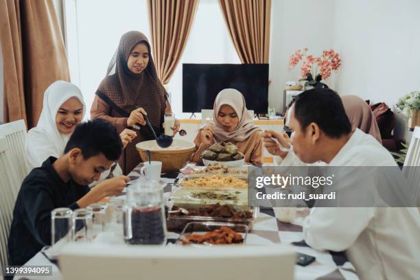 gruppo di amici riuniti intorno al tavolo con cibo e bevande, divertersi insieme - muslim family foto e immagini stock