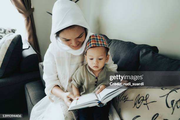 sohn und mutter lesen zu hause gemeinsam den koran - god is love stock-fotos und bilder