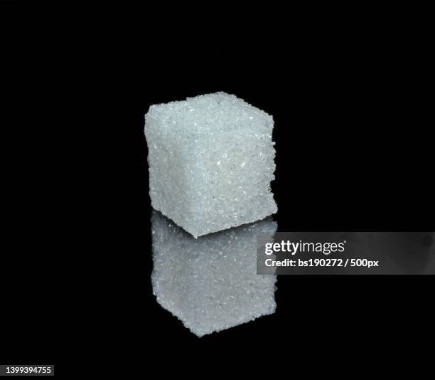 white sugar cube from crystals on black glossy glass - sugar cube stock pictures, royalty-free photos & images