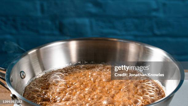 close up bubbling sugar caramelizing in pan - pot of gold stock-fotos und bilder