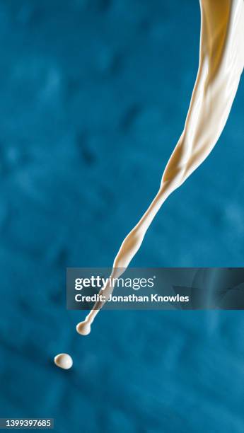 milk stream and droplet midair - milk stream stock pictures, royalty-free photos & images