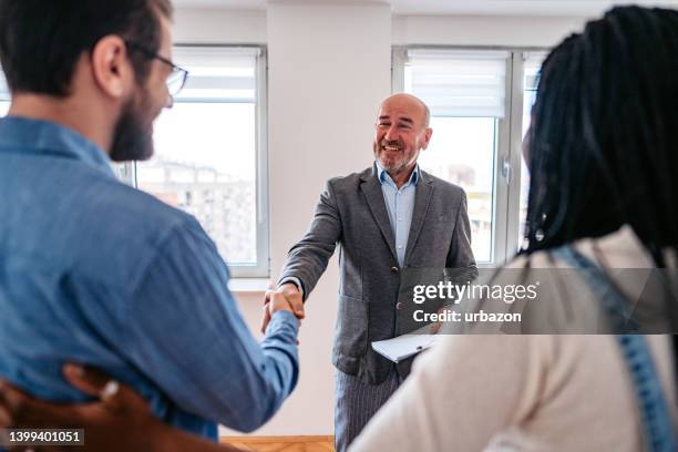 real estate agent showing an apartment to the young couple - huurhuis stockfoto's en -beelden