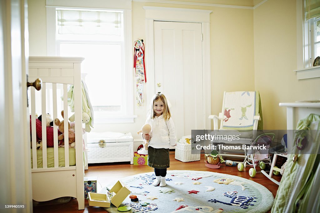 Young girl standing in bedroom smiling