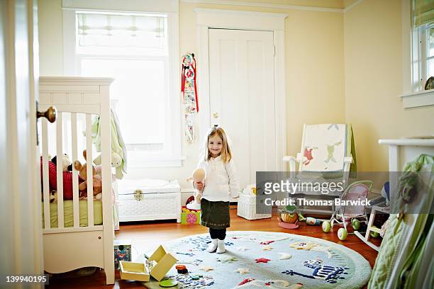 young girl standing in bedroom smiling - bambola giocattolo foto e immagini stock