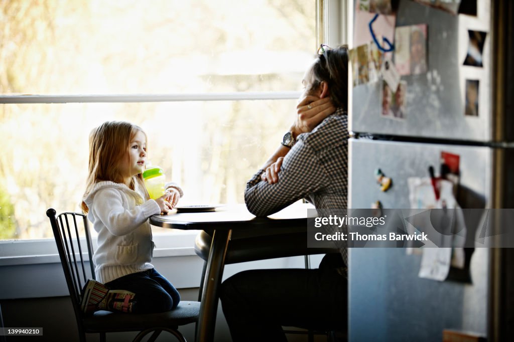 Father and daughter sitting at table in kitchen