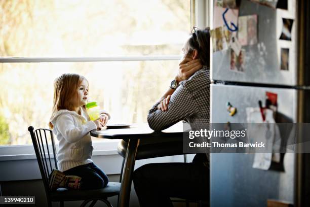 father and daughter sitting at table in kitchen - leanincollection father photos et images de collection