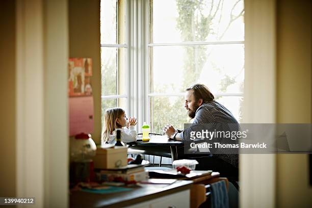 father and daughter sitting at table in discussion - neue männlichkeit stock-fotos und bilder