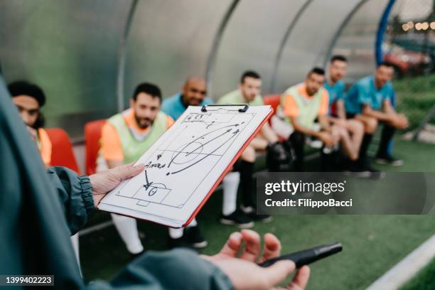 the coach is explaining the tactics to the soccer team - side lines stockfoto's en -beelden