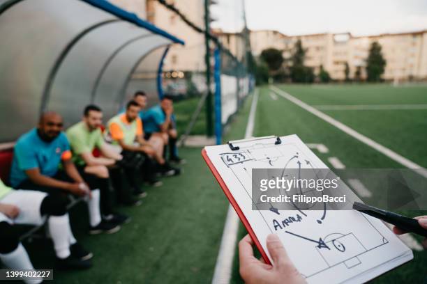 the coach is explaining the tactics to the soccer team - treinador imagens e fotografias de stock