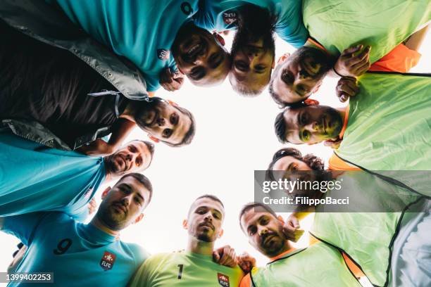 low-angle-ansicht einer fußballmannschaft, die sich zusammenkauert - blick nach unten stock-fotos und bilder