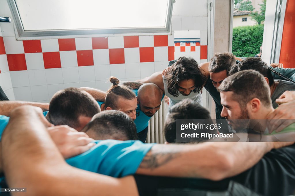 Soccer team players are huddling together in the locker room