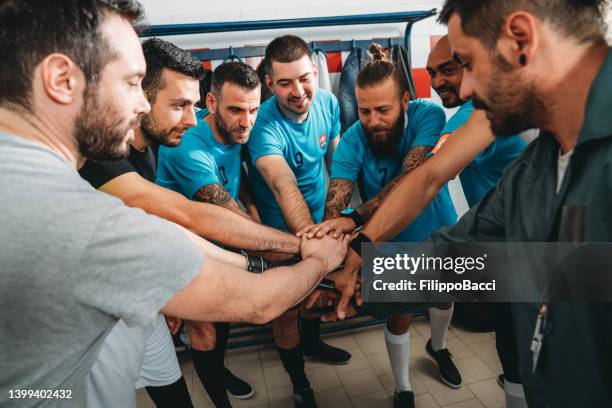 fußballspieler drängen sich in der umkleidekabine zusammen - vereinscoaching stock-fotos und bilder