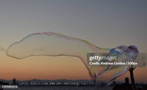 silhouette of people blowing large bubbles against sky during sunset,greece - big bubble foto e immagini stock