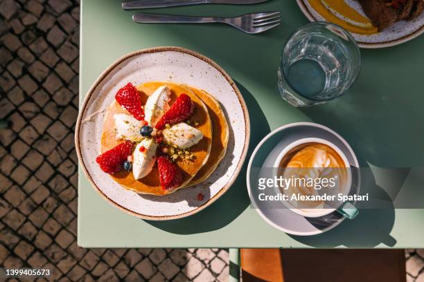 pancakes with strawberry served with latte for breakfast at the cafe - sunlight through drink glass stock-fotos und bilder