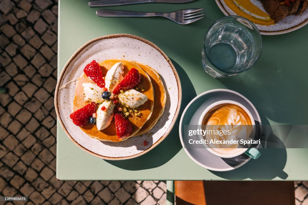 Pancakes with strawberry served with latte for breakfast at the cafe