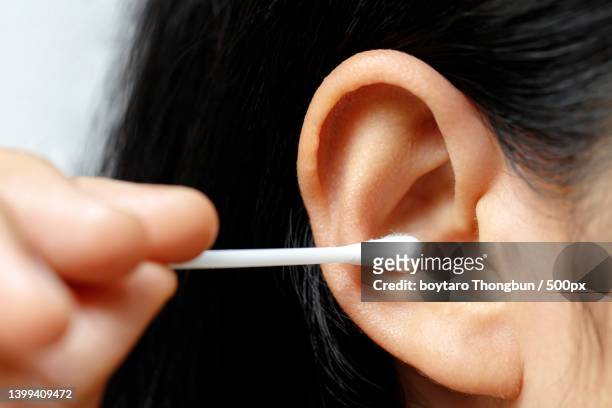 close-up of woman using ear cleaner swab - ear close up women stock-fotos und bilder