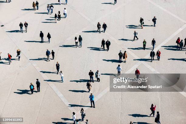aerial view of large number of people walking on the city square on the sunny day - silueta persona cenital fotografías e imágenes de stock