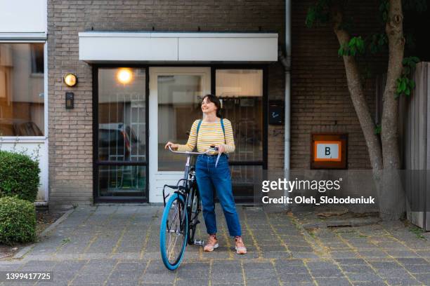 woman on bicycle in the residential neighbourhood - district stockfoto's en -beelden