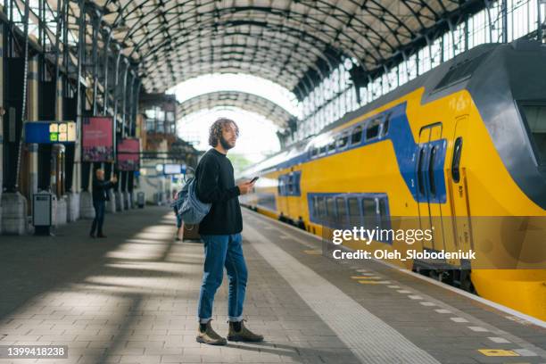 hombre esperando el tren en la estación de tren - trein nederland fotografías e imágenes de stock