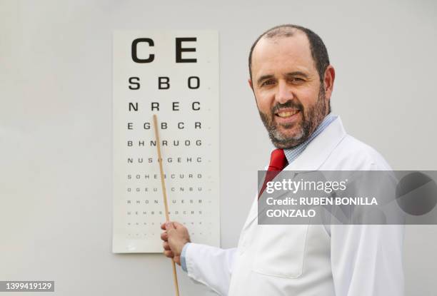 ophthalmologist doctor wearing lab coat with the snellen chart. healthcare and medicine concept. - sehtest stock-fotos und bilder