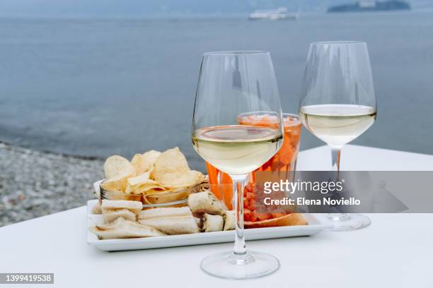 aperitif two glasses of white wine with antipasto cheese and salami, olives - table aperitif stock pictures, royalty-free photos & images