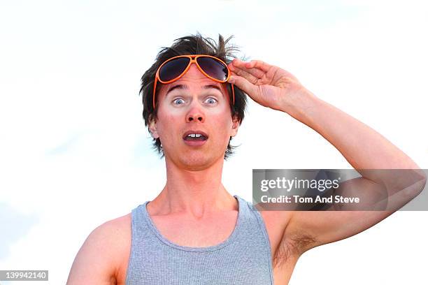 man raises his sunglasses in shock of his sunburn - sunburnt stock pictures, royalty-free photos & images