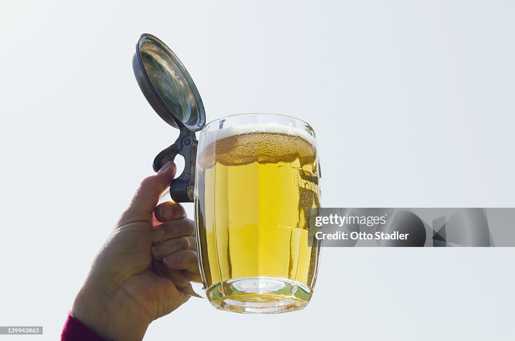 Hand holds a glass of beer in the sky