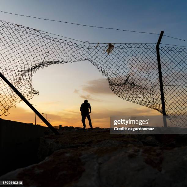 refugee man running behind fence - prison fence stock pictures, royalty-free photos & images