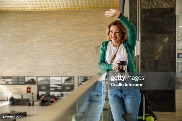 femme saluant quelqu’un au loin en attendant un train à la gare - woman waving goodbye photos et images de collection