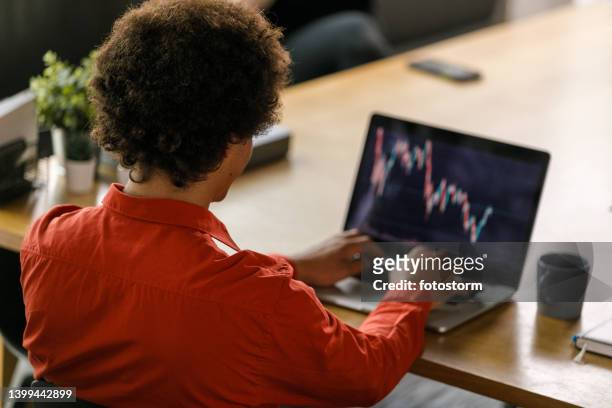 businessman sitting at his desk, making a graph on laptop - working behind laptop stockfoto's en -beelden